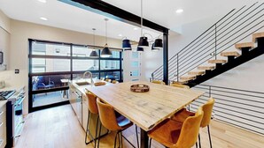 Eine moderne Küche mit einem Holztisch und -stühlen, einer Treppe und einem großen Fenster.