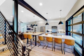 A modern kitchen with a central island, bar stools, pendant lighting, and large windows. - Newly built home with pool, hot tub, & gym - walk to gondola (Steamboat Springs)