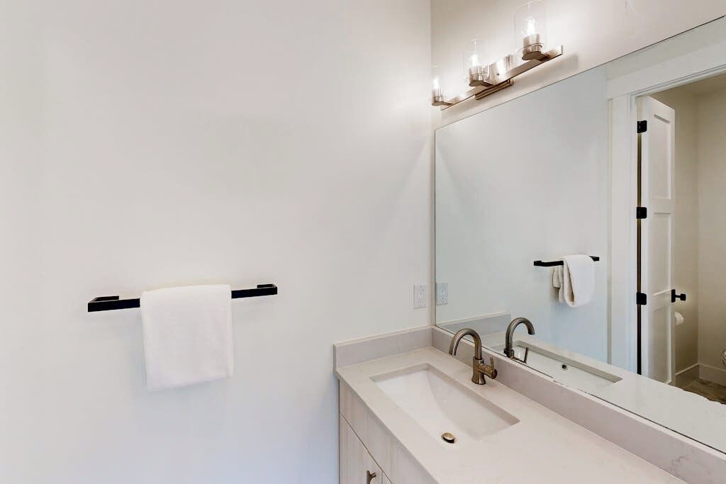 Un baño moderno con un espejo grande, un lavabo y un perchero para toallas.