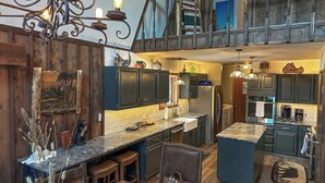 Une cuisine spacieuse avec un plafond haut, des meubles en bois foncé et un îlot central.