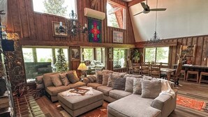 Un salon spacieux avec un grand canapé d’angle, une cheminée et un coin repas doté de meubles en bois.