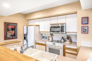 Eine moderne Küche mit weißen Schränken, Edelstahlgeräten und einer Holz Arbeitsplatte.