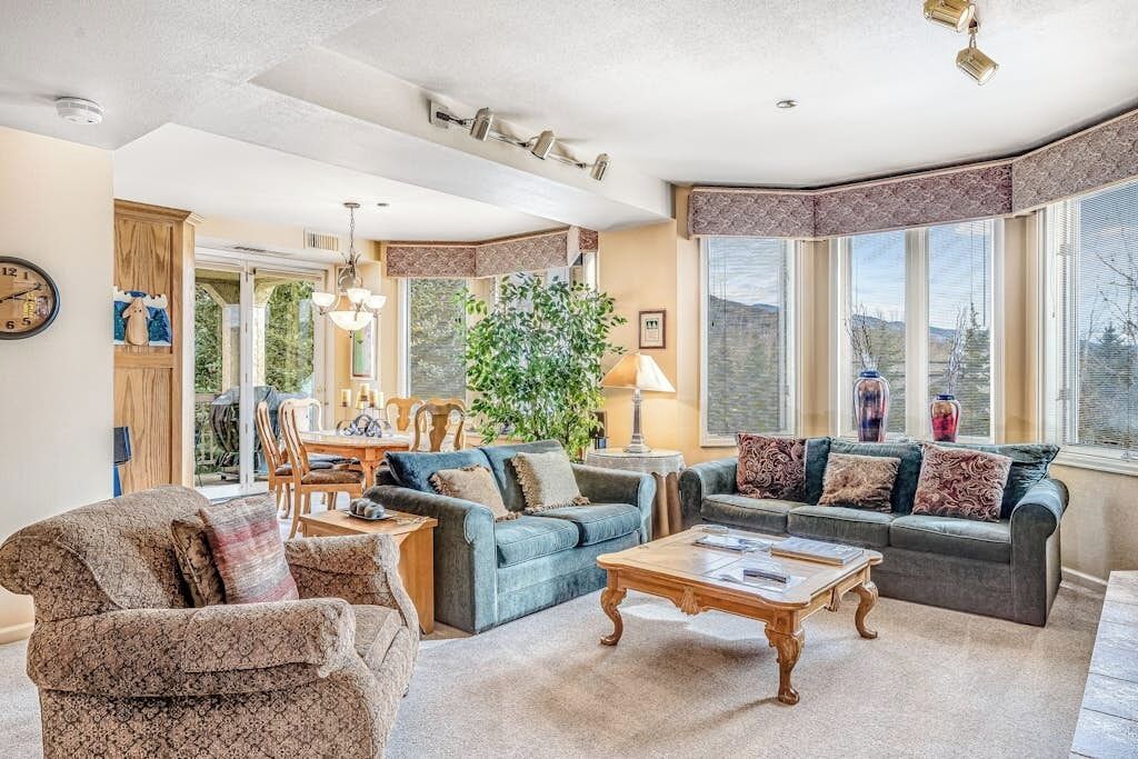 A living room with a sofa set, a coffee table, and a dining area with chairs and a table.