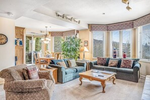 Ein Wohnzimmer mit einer Sofagarnitur, einem Couchtisch und einem Essbereich mit Stühlen und einem Tisch.