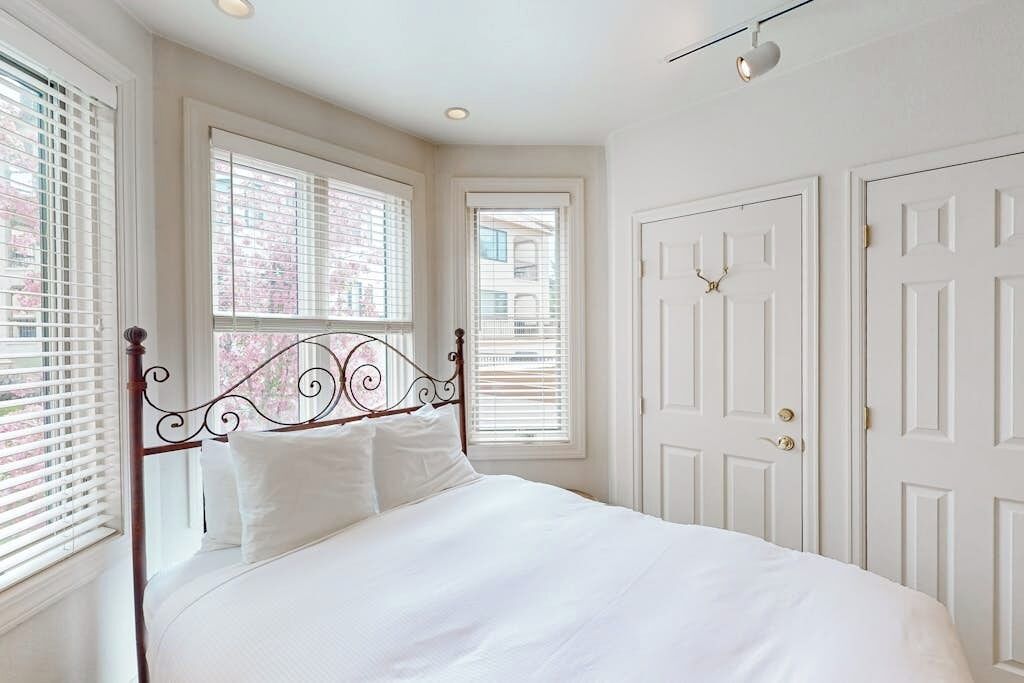 A bedroom with a bed, white walls, and a door.