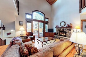 Ein geräumiges Wohnzimmer mit Kamin, großen Fenstern und einer gemütlichen Sitzecke.