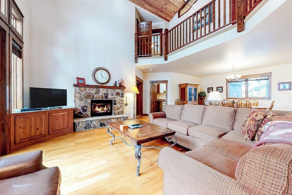 A spacious living room with a fireplace, a television, a sofa, and a staircase leading to an upper level.