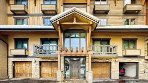 A multi-story building with a central entrance, balconies, and a parking area. - Luxury condo next to lift with pool, hot tubs & high-speed WiFi (Steamboat Springs)