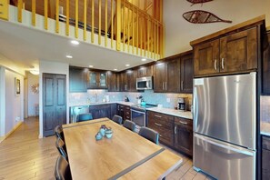 Eine moderne Küche mit Holzschränken, Edelstahlgeräten und einem Essbereich mit einem Holztisch.