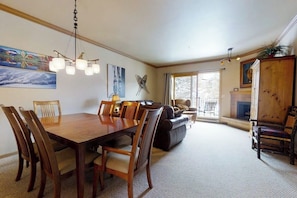 A dining area with a wooden table and chairs, a chandelier, and artwork on the walls. - Charming condo just steps to base area w/shared pool, hot tub, free WiFi (Steamboat Springs)