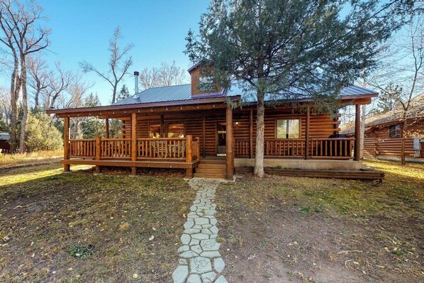 A log cabin with a porch, stone pathway, and a large tree in front. - Ideal Gem on the River w/ Wood-Burning Fireplace, Spacious Deck, & WiFi (South Fork)