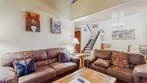 Ein Wohnzimmer mit zwei braunen Ledersofas, einem Holztisch und einer Treppe, die zu einer oberen Ebene führt.