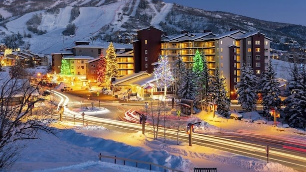 Een hotel met meerdere verdiepingen, een skipiste op de achtergrond en een besneeerd landschap.