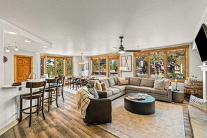Ein geräumiges Wohnzimmer mit einer großen Eckcouch, einem Couchtisch und einer Essecke mit Barhocker.