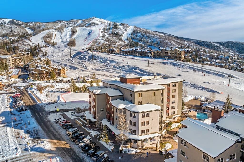 Une station de ski enneigée, dotée d’un hôtel à plusieurs étages, d’un parking et de pistes de ski.