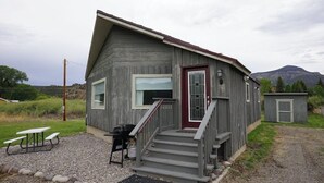 Eine Holzhütte mit einer Veranda, einem kleinen Anbau und einem Picknicktisch.