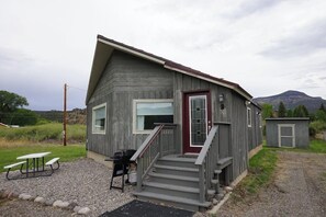Eine Holzhütte mit einer Veranda, einem kleinen Anbau und einem Picknicktisch.