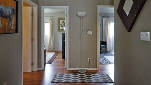 Ein Flur mit einem gemusterten Teppich, einer Stehlampe und einem Spiegel an der Wand.