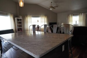 Eine Küche mit Marmorarbeitsplatte, Deckenventilator und Essbereich mit Stühlen und Tisch.