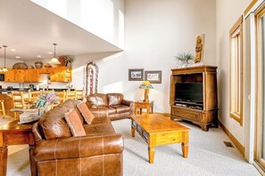 Ein Wohnzimmer mit einem braunen Ledersofa, einem Holztisch und einem Fernseher.