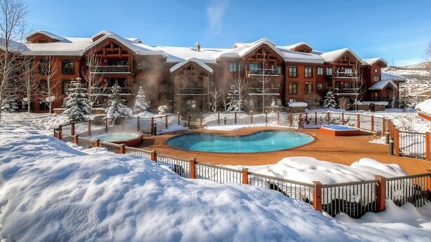 Ein großes Chalet mit Schwimmbad, umgeben von Schnee.