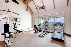 A gym with exercise equipment, a treadmill, and large windows with a view. - Loft condo with Flattop Mountain views, shared hot tubs, gas fireplace, & gym (Steamboat Springs)