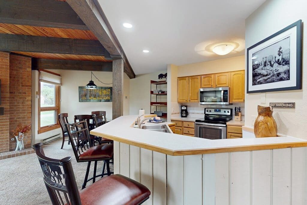 A kitchen with a central island, wooden cabinets, a microwave, and a coffee maker.