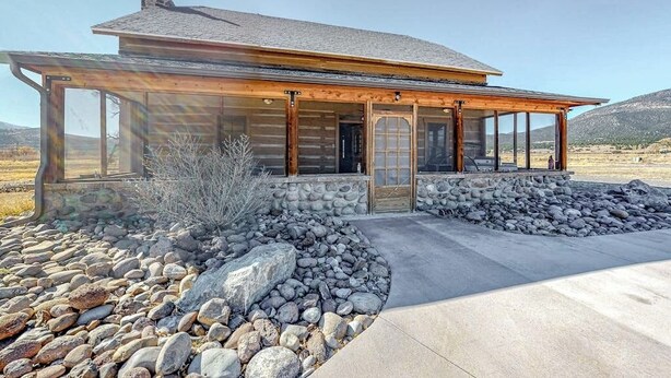 A log cabin with a stone foundation, large windows, and a stone retaining wall. - Dog-friendly riverfront retreat with hot tub, stunning views & screened porch (South Fork)