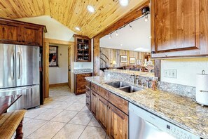 Eine Küche mit Holzausstattung, Granit-Arbeitsplatten, Edelstahlgeräten und einem integrierten Geschirrspüler.