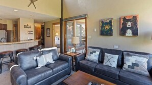 A living room with two sofas, a coffee table, and a kitchen in the background. - The Lodge at Steamboat A301 Upscale condo with balcony, pool, hot tubs, & fireplace - walk to lifts (Steamboat Springs)