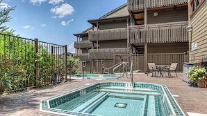 A pool area with two rectangular pools, a wooden fence, and a building with balconies. - The Lodge at Steamboat A301 Upscale condo with balcony, pool, hot tubs, & fireplace - walk to lifts (Steamboat Springs)