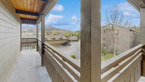 Un balcón cubierto con vistas a una zona residencial, que incluye casas y una montaña al fondo.