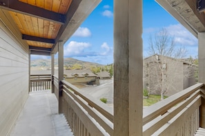 A covered balcony with a view of a residential area, including houses and a mountain in the distance. - Luxurious mountain condo with pool, hot tubs & patio - near Steamboat ski lifts (Steamboat Springs)