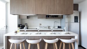 Una cucina moderna con mobili in legno, un'isola centrale con sgabelli da bar e un frigorifero integrato.