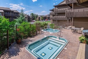 A rooftop pool area with two pools, surrounded by a fence and potted plants. - Classic Steamboat lodge-style condo with hot tubs & pool (Steamboat Springs)