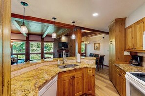 A kitchen with granite countertops, wooden cabinets, a built-in oven, and a large window overlooking greenery. - Classic Steamboat lodge-style condo with hot tubs & pool (Steamboat Springs)