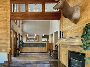 A lobby with a wooden reception desk, a fireplace, and a mounted animal head. - Large suite in Steamboat Springs with pool & hot tubs (Steamboat Springs)