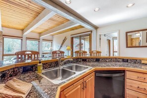 A kitchen with granite countertops, wooden cabinets, a double sink, and a dishwasher. - Perfect Steamboat getaway with hot tubs, pool, washer/dryer & free shuttle (Steamboat Springs)