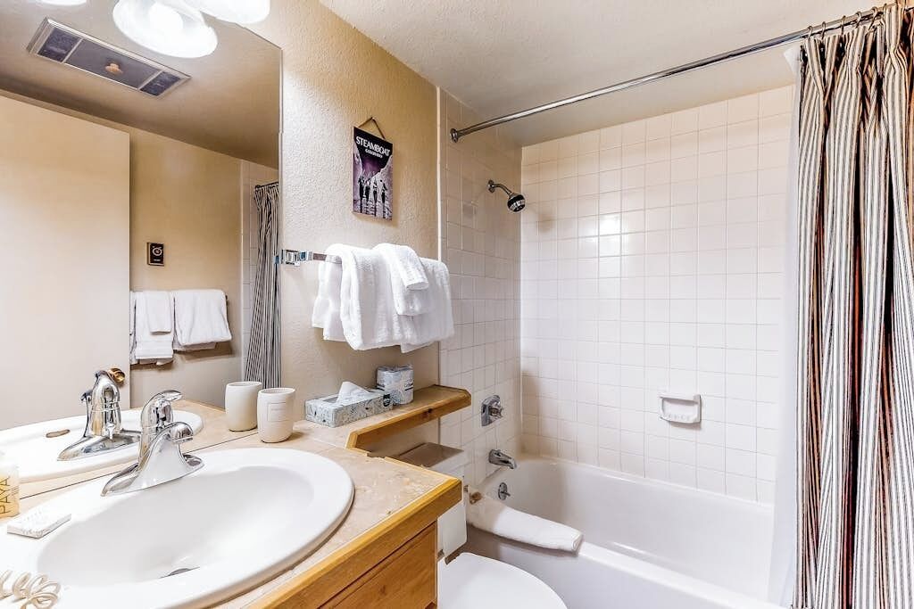 A bathroom with a sink, mirror, towel rack, shower, and bathtub.