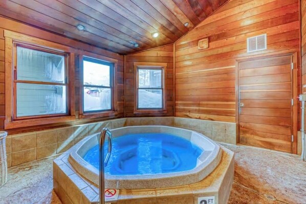 Ein Holzblock-Interieur mit Whirlpool, großen Fenstern und einer Tür.