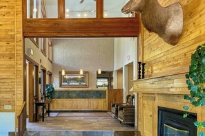 Eine Lobby mit Holzwänden, Steinboden, Kamin und einem aufgehängten Tierkopf.