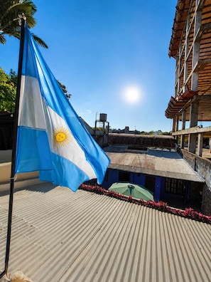 A corrugated metal roof, a flagpole with a flag, and a building with a traditional architectural style. - Complex, ideal for delegations, teams, travel groups or contingents. (Resistencia)