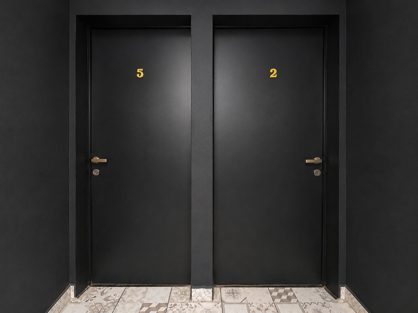 Dos puertas negras con los números 5 y 2, y un suelo estampado.