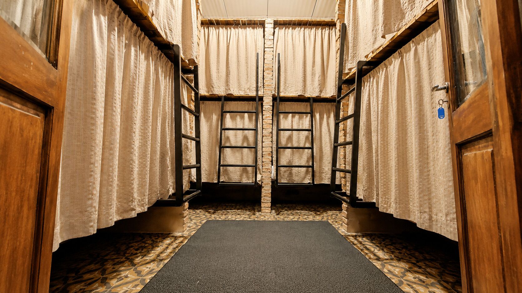 Un couloir étroit aux murs en bois, un tapis à motifs et une fenêtre avec un rideau.
