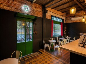 Interior de restaurante con paredes de ladrillo, puertas verdes y suelo de baldosas.
