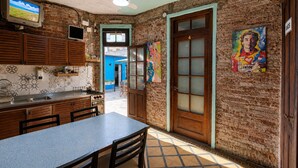 A kitchen with a dining area, a TV, and a door with frosted glass panels.