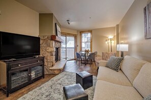 A living room with a television, stone fireplace, dining area, and a sofa. - Keystone Condo w/Mountain Views, Shared Pool/Hot Tub - Near Ski Lift/Restaurants (Keystone)