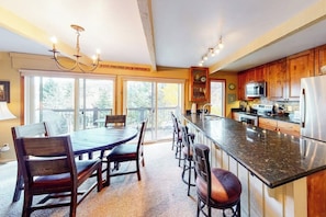 A spacious kitchen with a large island, wooden cabinets, and a dining area with a table and chairs. - Inviting Snowmass condo short walk from activities with balcony (Snowmass Village)
