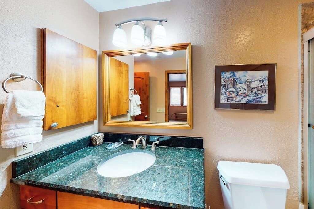 A bathroom with a sink, mirror, towel rack, and toilet.