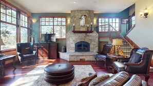 A spacious living room with a stone fireplace, leather furniture, and large windows. - Luxury mountain estate w/ private hot tub, home theater, two W/Ds, & spa (Keystone)